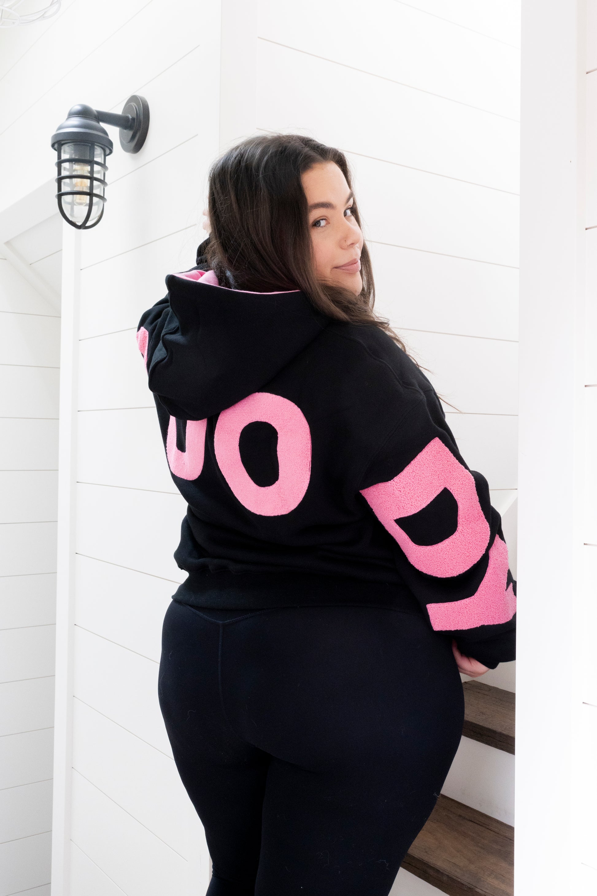 Women wearing a Mooody unisex hoodie black and pink, back view